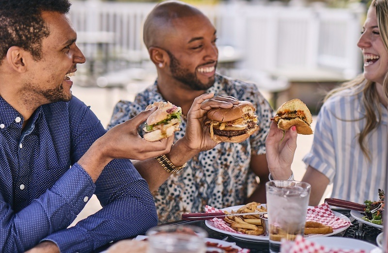 Two men and a woman enjoying burgers